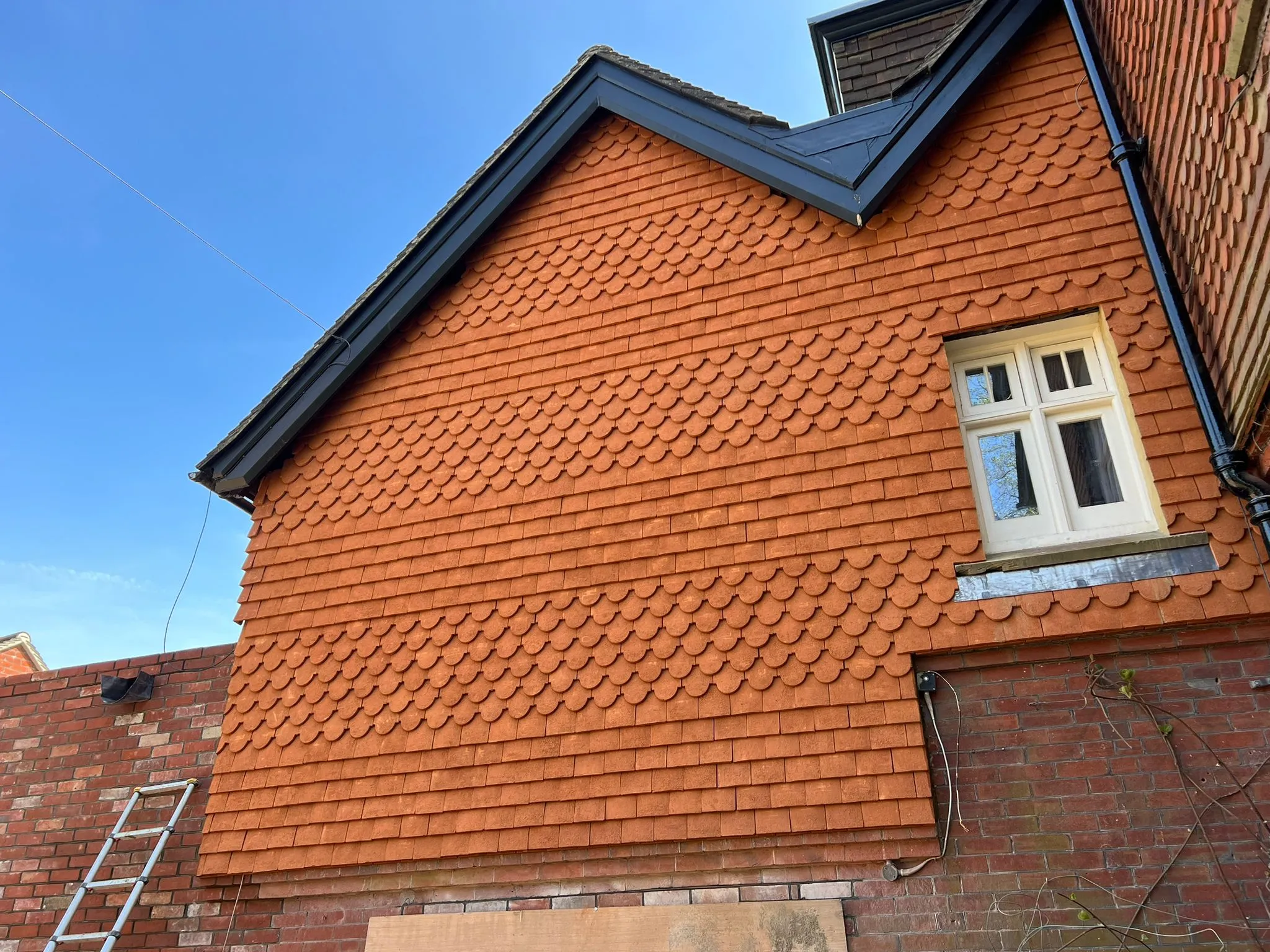 a red brick building with a window and a ladder